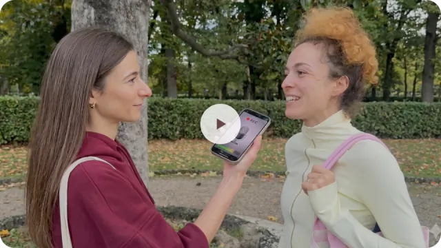 Gaia smiling at her friend who is showing her phone — recording her 4-week transformation story