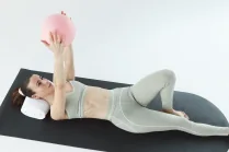 Esercizio di Pilates post parto: Carlotta Gagna distesa su un tappetino che tiene una palla da Pilates sopra il petto, per rinforzare il core e la parete addominale e ridurre la diastasi, nel programma Pilates Diastasi e Post Parto