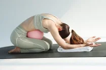 Esercizio di Pilates post parto: Carlotta Gagna in raccoglimento in avanti su un tappetino con una palla da Pilates all'addome, per distendere la schiena e rilassare il pavimento pelvico, nel programma Pilates Diastasi e Post Parto