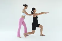 Esercizio di Pilates in gravidanza: Carlotta Gagna corregge la postura di una donna incinta in affondo con le braccia distese in avanti, per tonificare le gambe e migliorare l'equilibrio, nel programma Pilates Linfodrenante® Gravidanza