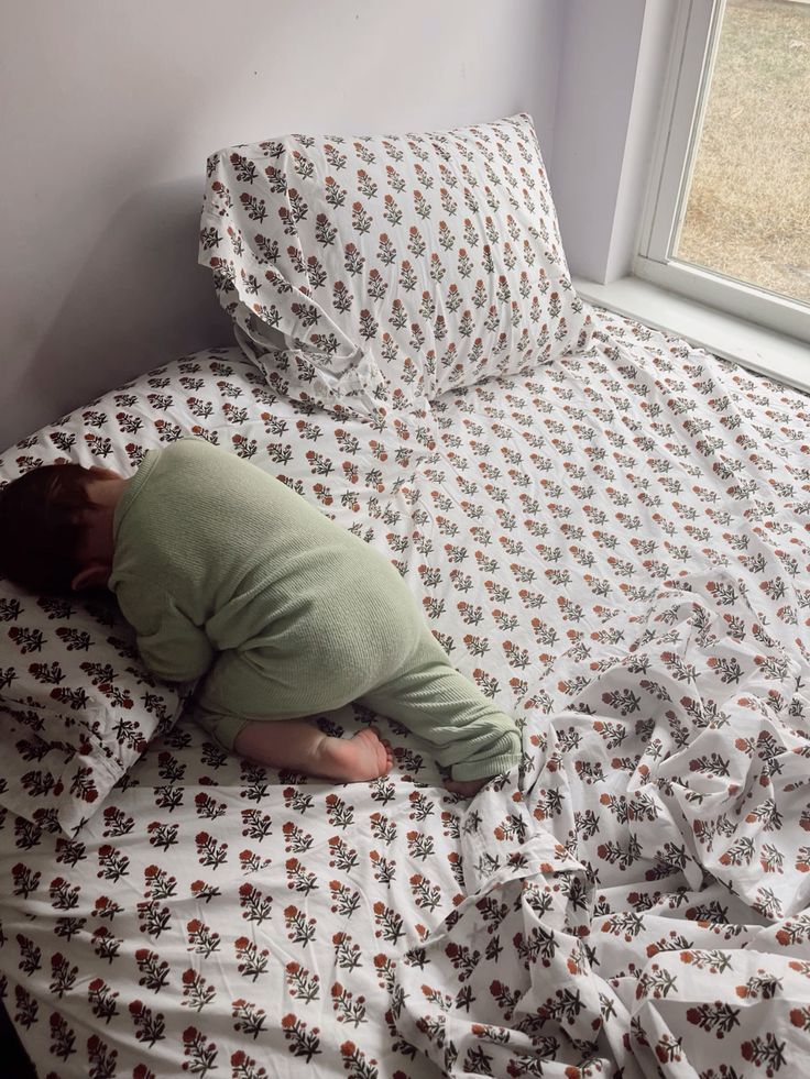 Bambino di pochi mesi addormentato sul cuscino di un letto matrimoniale