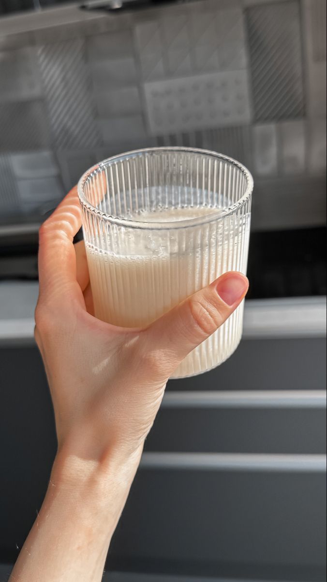Mano che regge un bicchiere in vetro con kefir al naturale