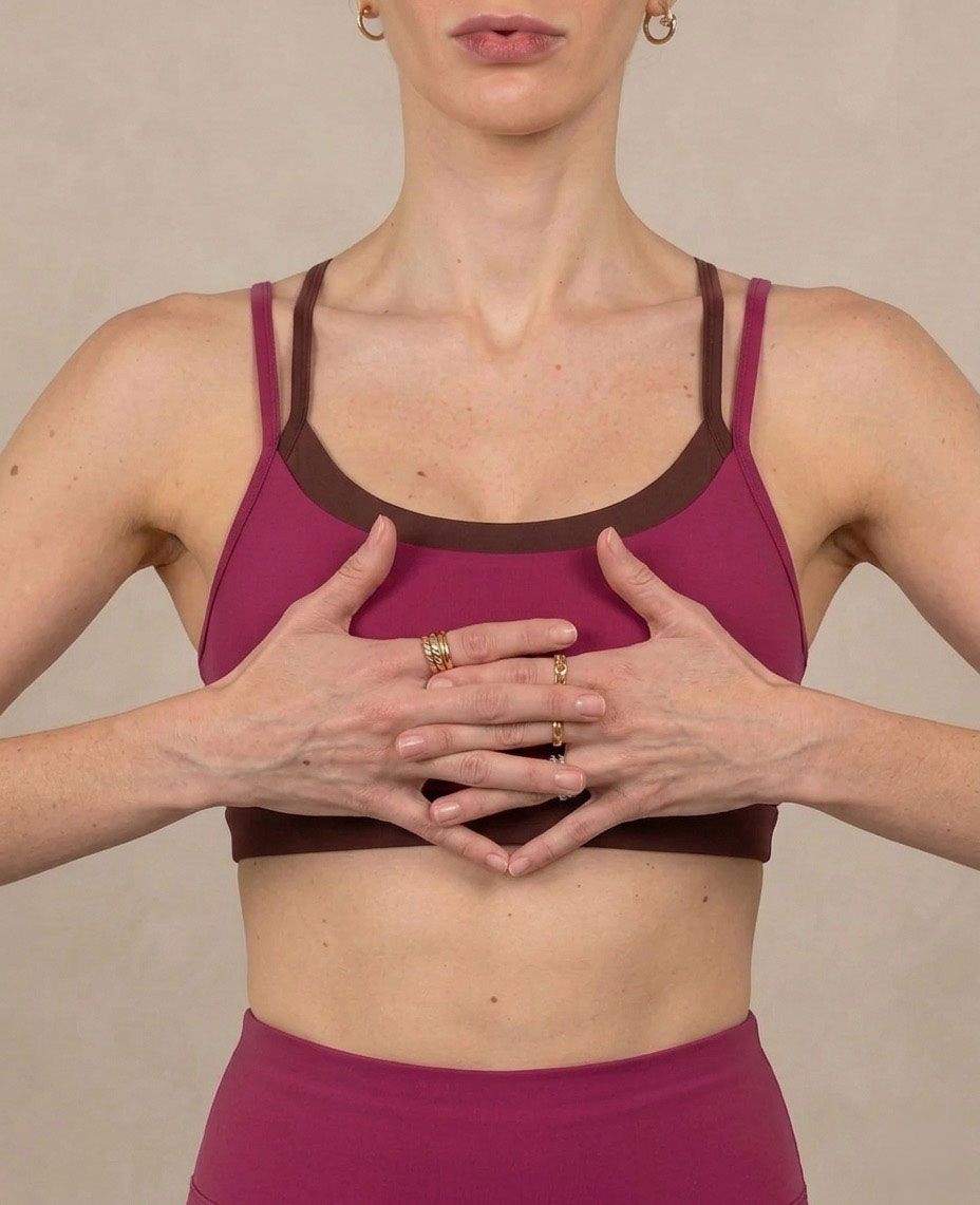 Busto di donna con mani al petto e dita intrecciate