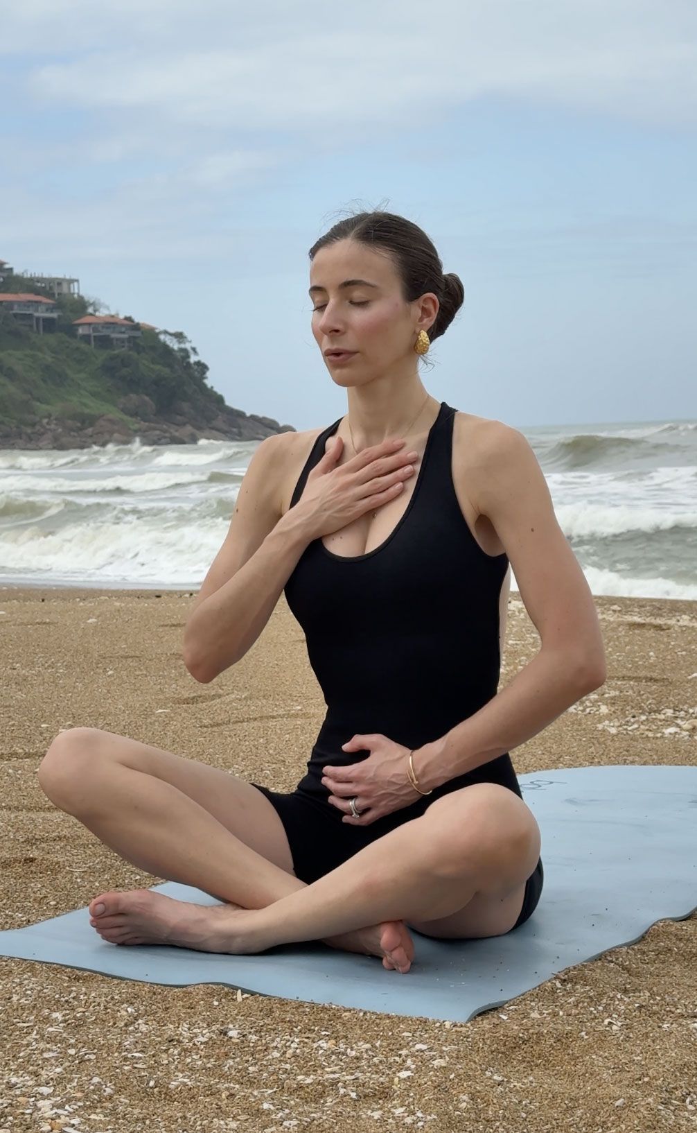 Carlotta Gagna practices diaphragmatic breathing with her hands on her chest and abdomen by the sea
