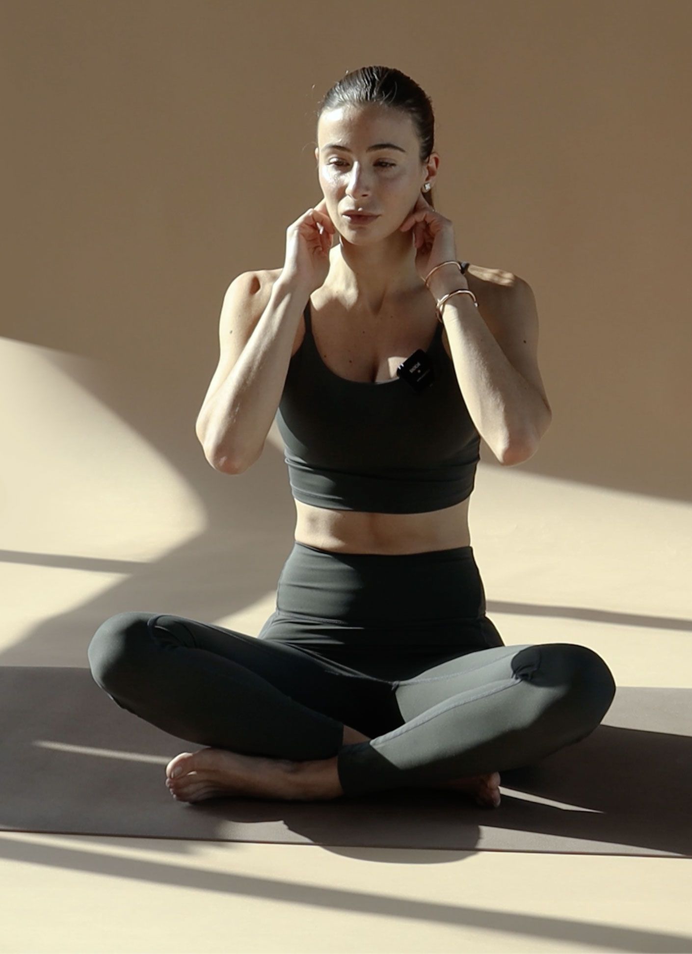 Carlotta Gagna sitting cross-legged and opening the lymph nodes under her ears