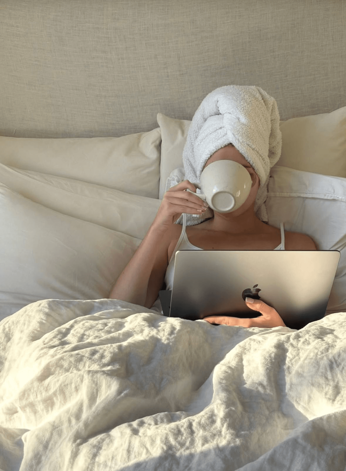 Donna a letto con laptop che beve una tisana — abitudine serale che disturba il sonno e peggiora l'insonnia