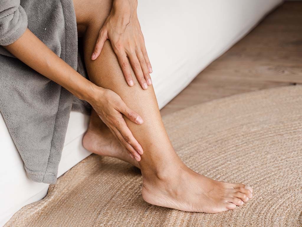 Donna tocca le gambe per verificare dolore al tatto e noduli — sintomi tipici del lipedema come sensibilità alla pressione e pelle irregolare