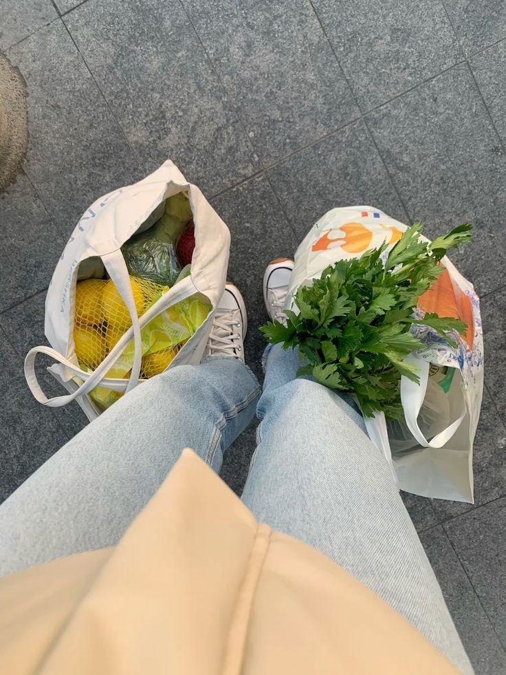 Donna in piedi con due borse della spesa colme di frutta e verdura