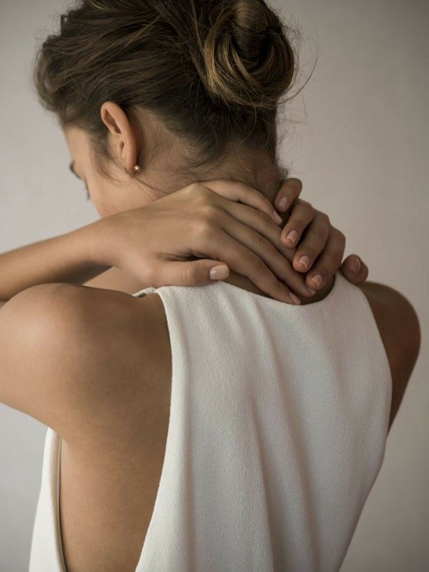 Donna di spalle con mani sul collo che massaggia la zona cervicale