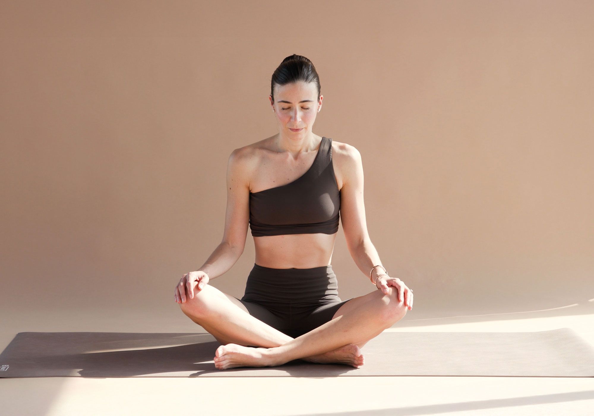 Carlotta Gagna seduta in posizione meditativa su tappetino, mani sulle ginocchia, durante la routine di drenaggio linfatico con il metodo Pilates Linfodrenante