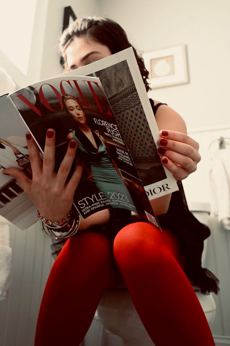 Donna che legge una rivista di moda mentre sta seduta sul wc