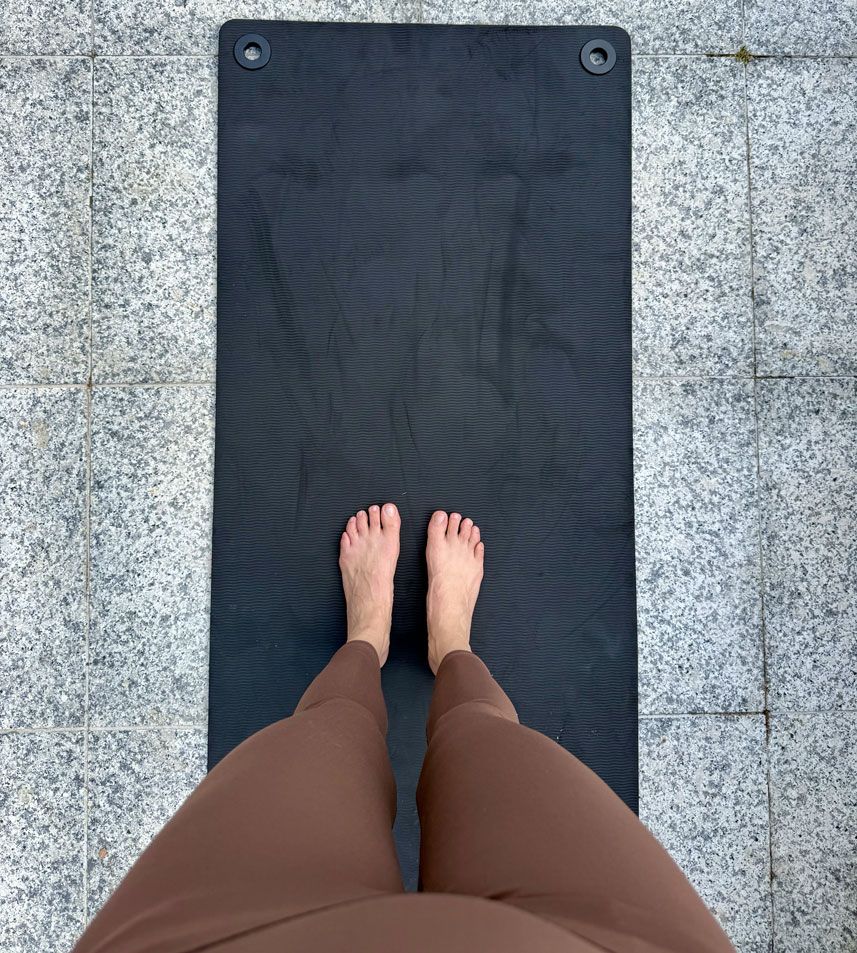 Piedi scalzi su tappetino Pilates visti dall'alto — inizio di una pratica quotidiana a basso impatto per gestire il lipedema e stimolare il drenaggio linfatico