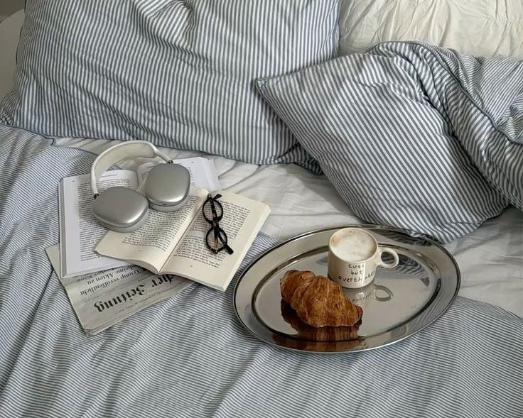 Letto con vassoio colazione, cuffie e libro — importanza di una routine serale rilassante per migliorare la qualità del sonno e combattere l'insonnia