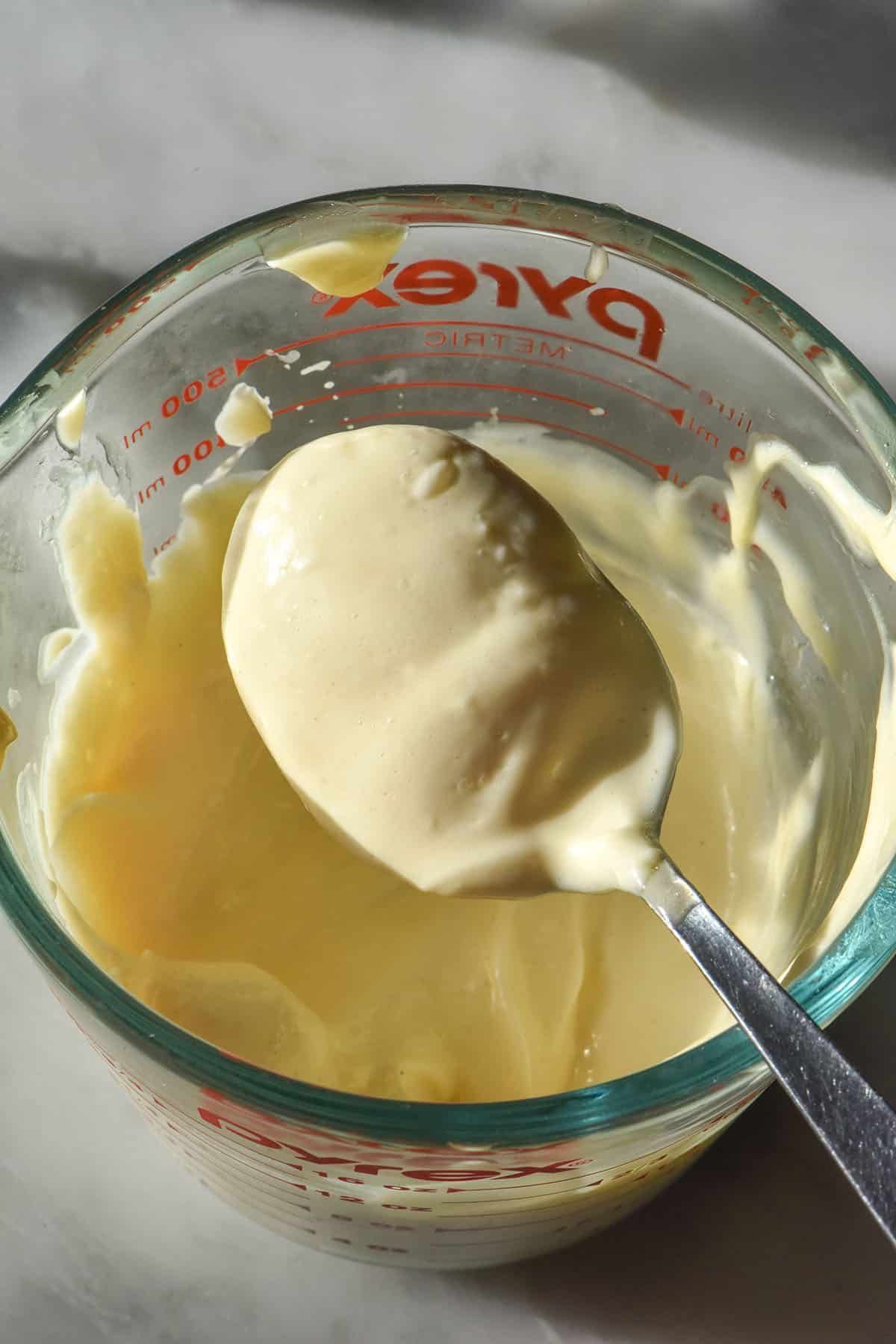 Cucchiaio e ciotola in vetro di maionese fatta in casa