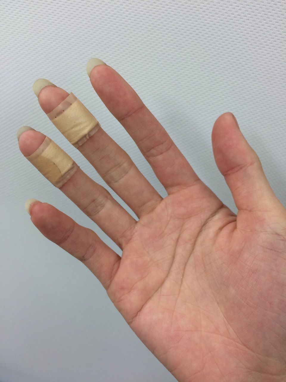 Palmo della mano di una donna con due cerotti su medio e anulare