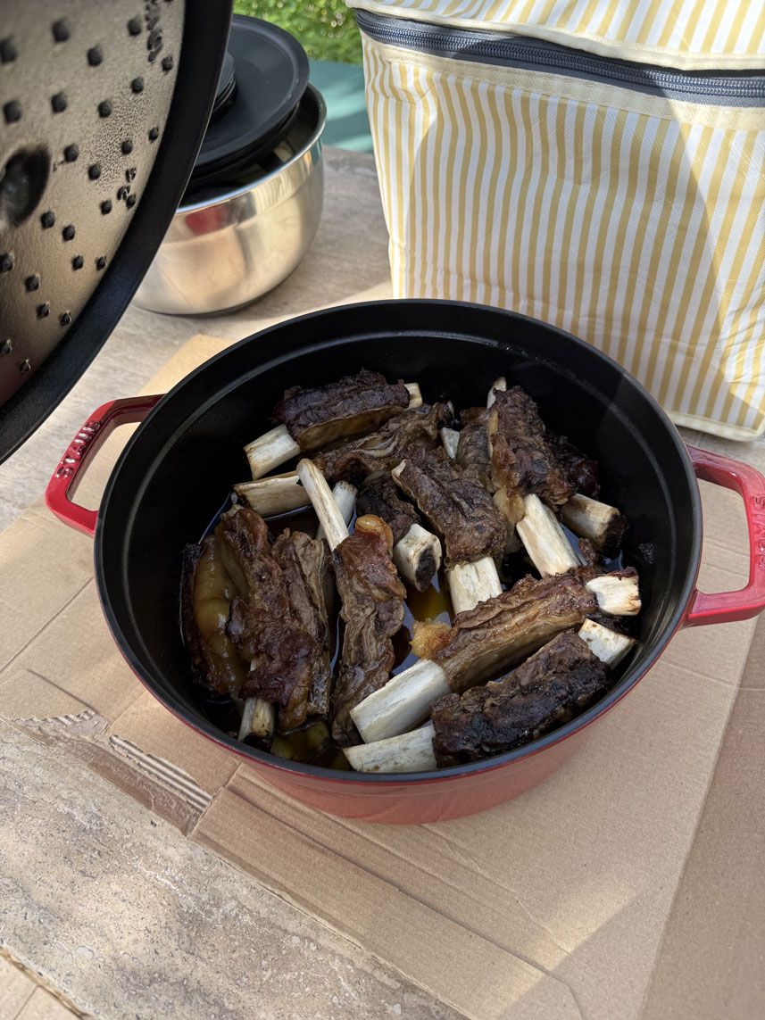 Costine che cuociono in una pentola Staub rossa in ghisa smaltata