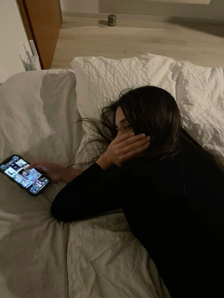 Donna a letto con smartphone acceso di notte — luce blu dello schermo che inibisce la melatonina alza il cortisolo e peggiora l'insonnia cronica