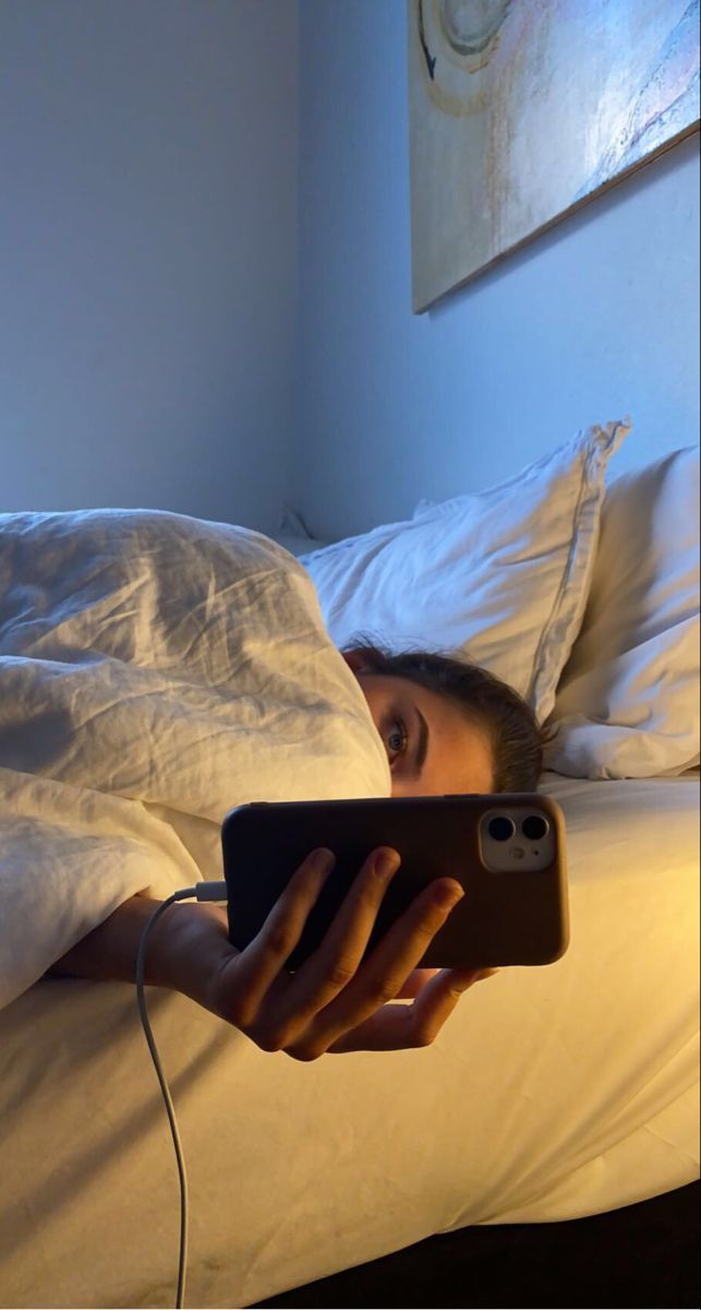 Donna a letto di notte con cellulare — abitudine che alza il cortisolo, disturba il sonno e peggiora il gonfiore addominale al mattino
