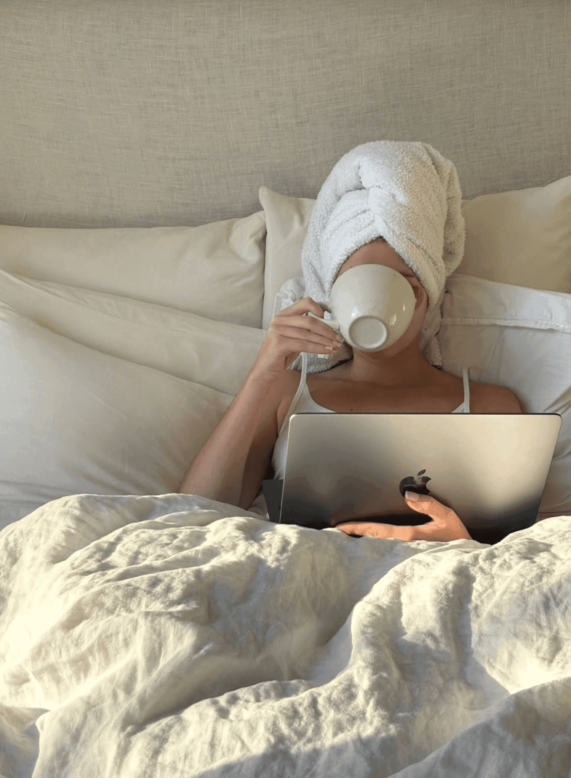 Woman in bed with laptop drinking herbal tea — a nighttime habit that disrupts sleep and worsens insomnia