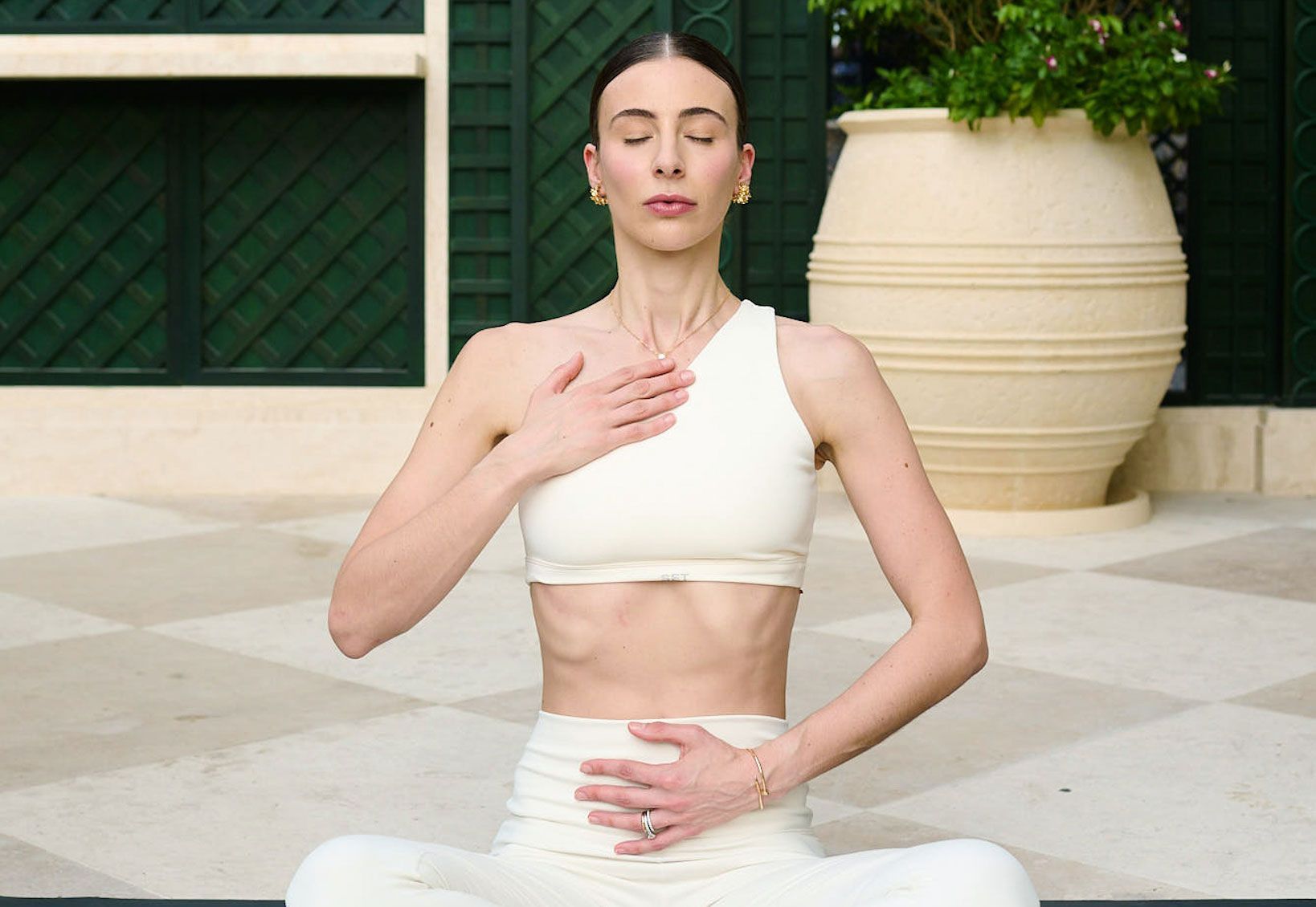 Woman sitting cross-legged with hands on chest performing a breathing exercise