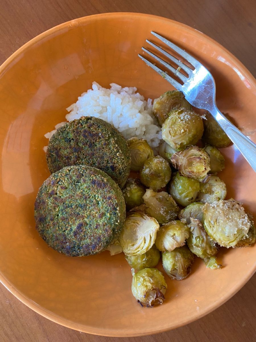 Piatto con burger vegetali di spinaci, riso bianco e cavoletti di Bruxelles