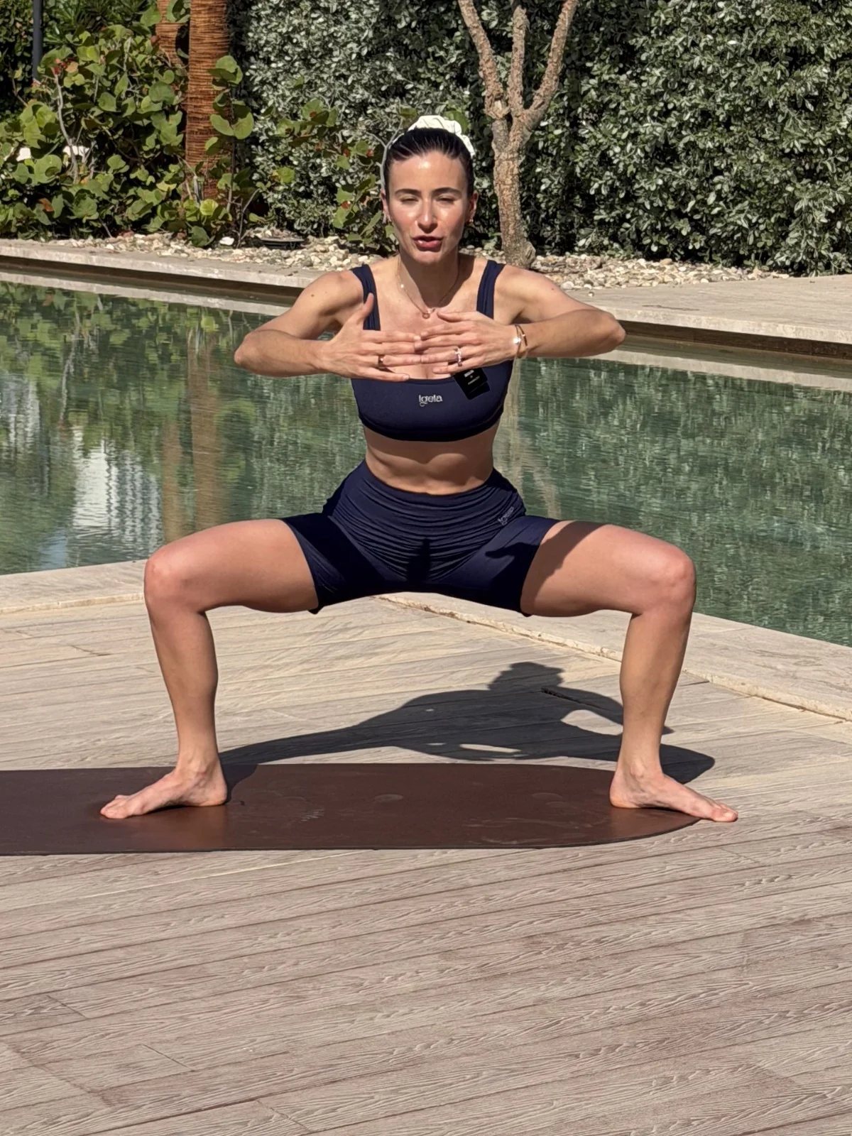Carlotta in sumo squat sul tappetino a bordo piscina