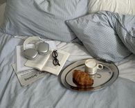 Bed with breakfast tray, headphones, and book — the importance of a relaxing evening routine to improve sleep quality and combat insomnia