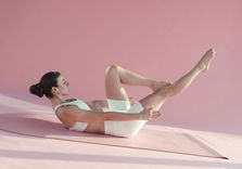 Carlotta Gagna lying on the mat with her knees to her chest to promote lymphatic drainage of the legs and relieve the feeling of heavy legs with Lymphatic Drainage Pilates.