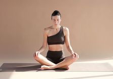 Carlotta Gagna seduta in posizione meditativa su tappetino, mani sulle ginocchia, durante la routine di drenaggio linfatico con il metodo Pilates Linfodrenante