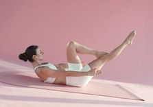 Carlotta Gagna sdraiata sul tappetino con ginocchia al petto per favorire il drenaggio linfatico delle gambe e alleviare la sensazione di gambe pesanti con il Pilates Linfodrenante