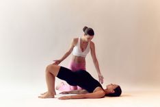Istruttrice di Pilates che supporta una incinta nell'esecuzione di un esercizio