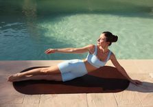 carlotta gagna lying on a mat by the poolside while performing a lymphatic drainage pilates exercise.jpg